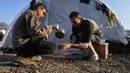 Seorang anak laki-laki membantu ayahnya mencuci tangan di kamp darurat tempat mereka menetap setelah kehilangan rumah akibat gempa bumi dahsyat, di kota Iskenderun, Turki selatan, Selasa (14/2/2023). Ribuan orang kehilangan tempat tinggal akibat gempa besar yang melanda Turki dan Suriah sepekan lalu, memadati tenda-tenda yang penuh sesak atau berbaris di jalan-jalan untuk makan panas saat pencarian korban selamat yang putus asa memasuki jam-jam terakhir. (AP Photo/Hussein Malla)