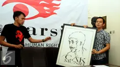 Direktur Imparsial Al Araf (kanan) memegang lukisan Munir jelang memberi keterangan di Jakarta, Selasa (6/9). Imparsial memandang pengungkapan kasus Munir adalah agenda penting penuntasan kasus pelanggaran HAM. (Liputan6.com/Helmi Fithriansyah)