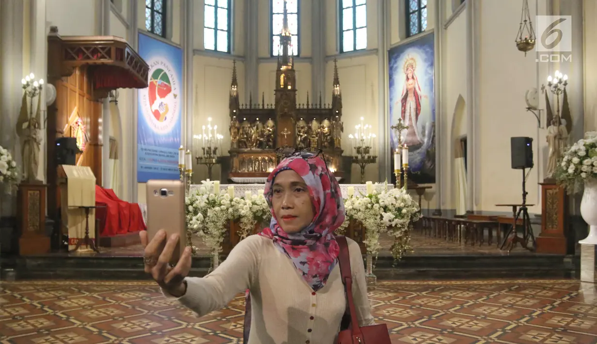Seorang umat muslin selfie di depan mimbar Gereja Katedral, Jakarta, Jumat (1/6). Kegiatan tersebut digelar komunitas Kerja Bakti Demi Negeri sambil buka puasa bersama. (Liputan6.com/Arya Manggala)