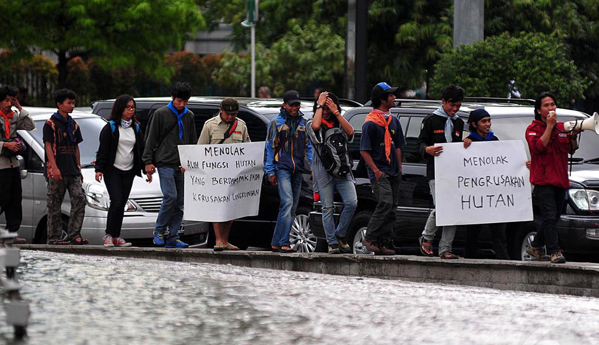 Mahasiswa tampak membentangkan spanduk sambil mengelilingi air mancur Bundaran HI Jakarta, Jumat (12/12/2014). (Liputan6.com/Johan Tallo)