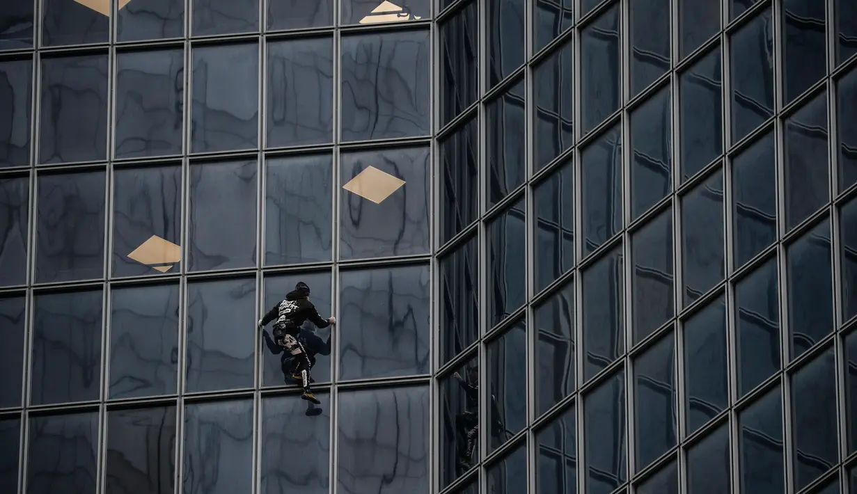 Pendaki Alain Robert atau French Spiderman memanjat Menara Total di kawasan bisnis La Defense, Paris, Prancis, Senin (13/1/2020). Alain memanjat gedung 48 lantai tersebut sebagai dukungan untuk pekerja yang mogok karena menentang reformasi pensiun di Prancis. (Thomas SAMSON/AFP)