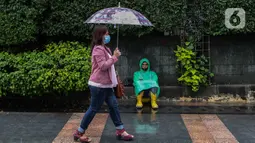 Seorang warga menggunakan payung saat hujan di kawasan Jakarta, Selasa (16/2/2021). Sebagai tahap awal vaksinasi COVID-19 tahap kedua bagi pekerja publik akan dimulai dari para pedagang Pasar Tanah Abang pada Rabu 17 Februari 2021. (Liputan6.com/Johan Tallo)