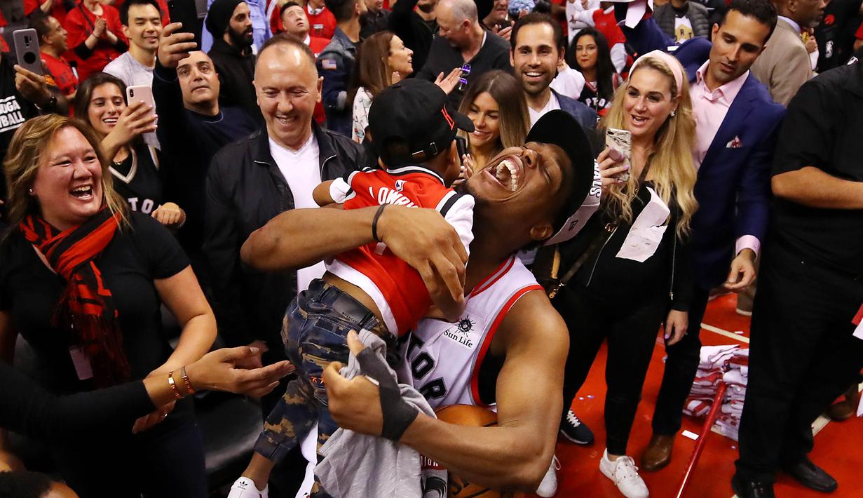 Pebasket Toronto Raptors, Kyle Lowry, menggendong putranya usai mengalahkan Milwaukee Bucks pada NBA Final Wilayah Timur di Scotiabank Arena, Toronto, Sabtu (25/5). Raptors menang 4-2 atas Bucks. (AFP/Gregory Shamus)