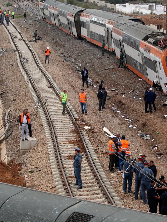 Aparat kepolisian berdiri dekat sebuah kereta api yang keluar jalur dan terguling di Sidi Bouknadel dekat ibu kota Rabat, Maroko, Selasa (16/10). Pihak berwenang Maroko menyatakan mereka sedang menyelidiki penyebab kecelakaan. (AP/Abdeljalil Bounhar)