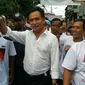 Yusril berjalan ke lokasi acara dan melambaikan tangan dari jauh pada warga Bidara Cina. (Nanda Perdana Putra/Liputan6.com)