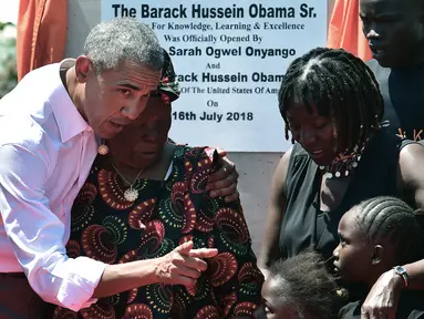 Mantan Presiden Amerika Serikat, Barack Obama bersama nenek tirinya, Sarah dan sang adik tiri, Auma serta beberapa pemuda setempat pada peresmian pusat pelatihan dan olahraga yayasan Sauti Kuu di Kogelo, Kenya, Senin (16/7). (AFP/TONY KARUMBA)