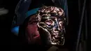 Fettler Piotr Lichon membuat topeng BAFTA (British Academy of Film and Television Arts) mask di New Pro Foundries, London, pada 21 Januari 2020. (JUSTIN TALLIS / AFP)