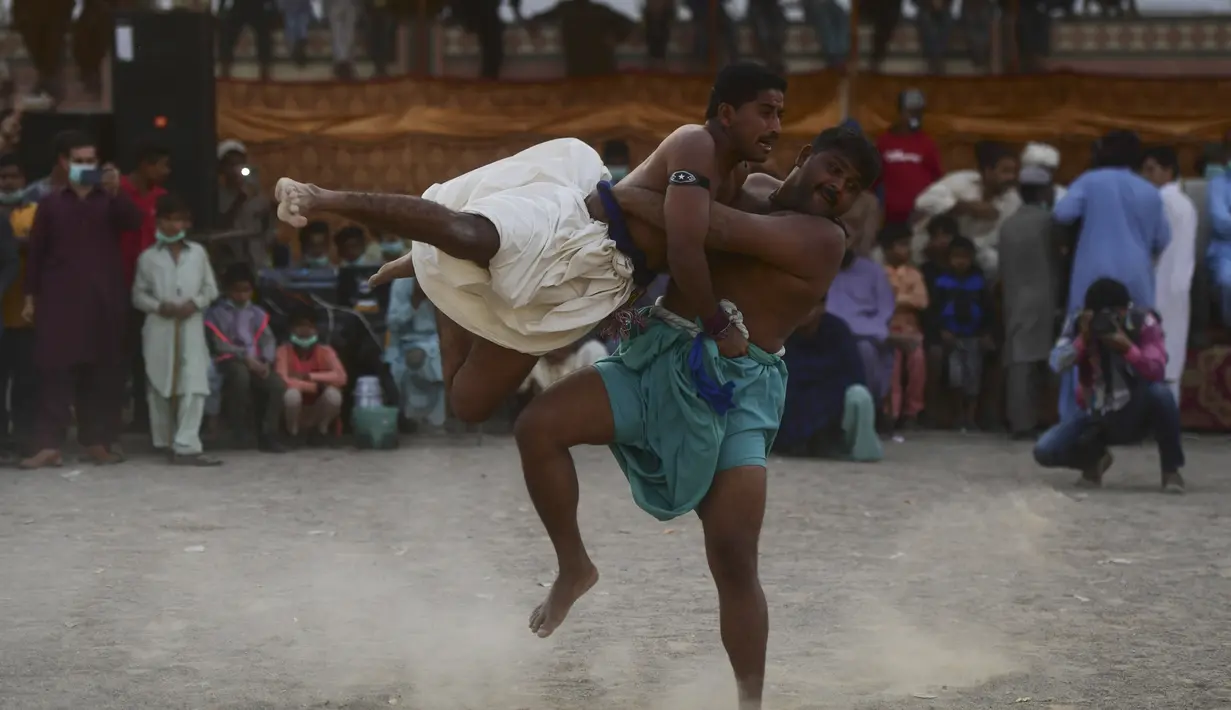 Pegulat bertarung selama turnamen gulat tradisional Sindhi Malakhra di kota pelabuhan Karachi, Pakistan pada Minggu (13/12/2020). Gulat kuno yang dimulai sejak 5.000 tahun lalu ini salah satu olahraga favorit di kalangan pria. (Photo by Asif HASSAN / AFP)