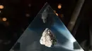 Batu dari Bulan terpajang dalam wadah kaca akrilik jelang perayaan 50 tahun misi Apollo di atas kapal USS Hornet, Alameda, California, Amerika Serikat, Selasa (16/7/2019). Astronot menyimpan batu Bulan ke dalam kotak penyimpanan dan membawanya ke Bumi. (JOSH EDELSON/AFP)