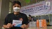 Atlet Bulutangkis Apriyani Rahayu menunjukkan kartu vaksin di Rumah Sakit Olahraga Nasional, Jakarta, Jumat (12/3/2021). Kemenpora bersama Kemenkes melakukan vaksinasi COVID-19 dosis ke-2 kepada insan olah raga nasional dengan menyasar 820 orang secara bertahap. (Liputan6.com/Herman Zakharia)