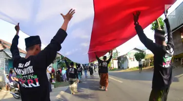 Sejumlah santri dari Pondok Pesantren Ashabul Kahfi membawa bendera Merah Putih besar saat mengikuti pawai Hari Santri Nasional 2017 di Gunungpati, Semarang (22/10). (Liputan6.com/Gholib)