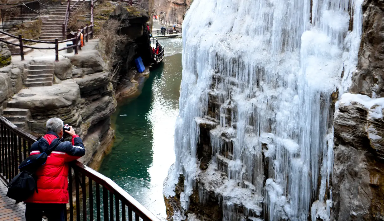 Seorang pengunjung memotret air terjun beku di objek wisata Gunung Yuntai di Jiaozuo, Provinsi Henan, China tengah, pada 24 Desember 2020. (Xinhua/Hao Yuan)