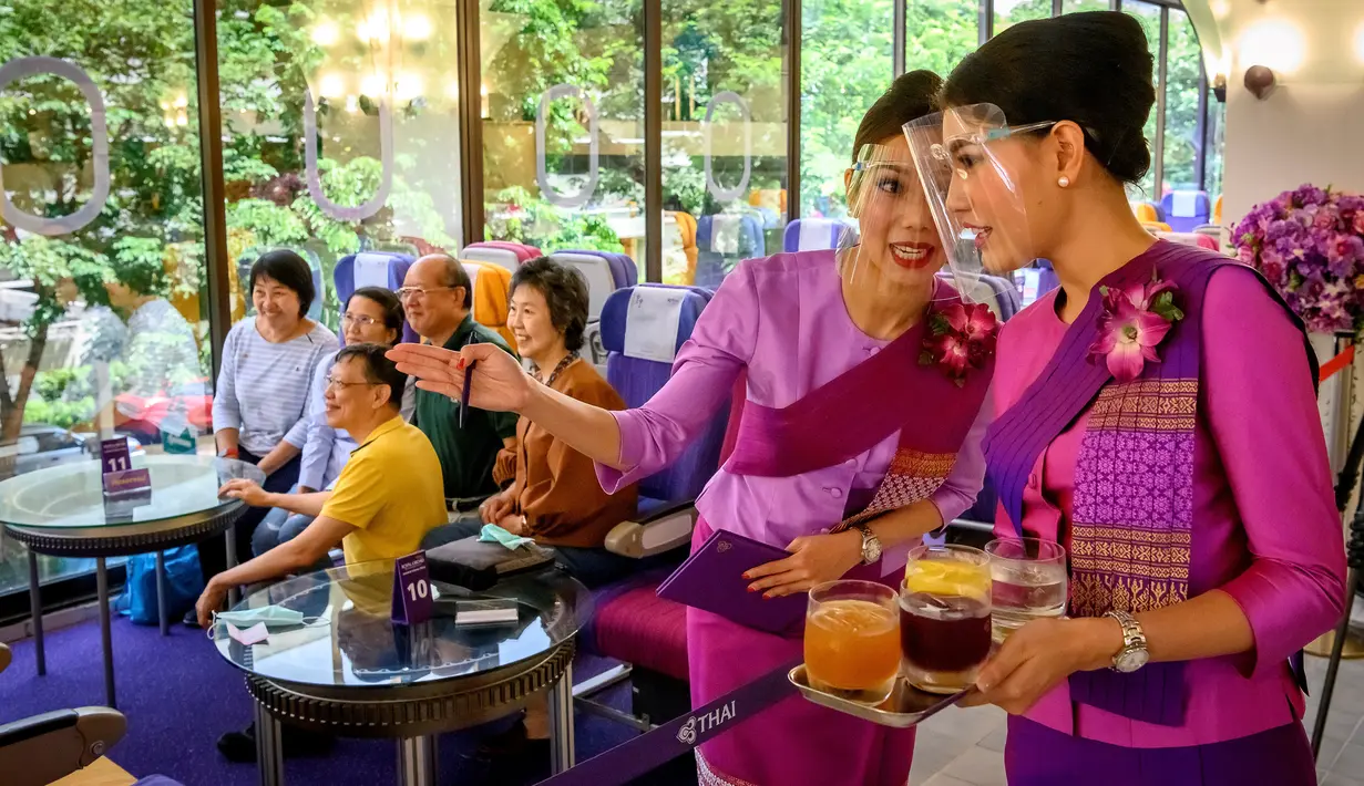 Pramugari mengenakan pelindung wajah saat melayani pelanggan di restoran pop-up bertema kabin pesawat di kantor pusat Thai Airways di Bangkok, 10 September 2020. Restoran pop-up ini awalnya hanya untuk sementara, tetapi antusias pengunjung membuat pihak maskapai berpikir ulang. (Mladen ANTONOV/AFP)
