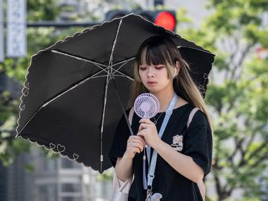 Seorang wanita menggunakan payung untuk berlindung dari sinar matahari saat berjalan di sepanjang jalan di Tokyo pada 19 September 2024. (Yuichi YAMAZAKI/AFP)