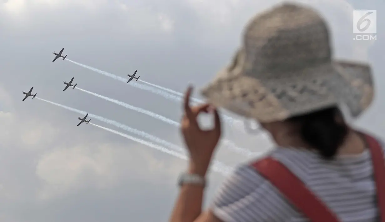 Warga menyaksikan atraksi Jupiter Aerobic Team TNI AU saat berlangsungnya pesta rakyat dalam rangka peringatan HUT TNI AU ke-72 di Lanud Halim Perdanakusumah, Jakarta, Sabtu (7/4). (Liputan6.com/Herman Zakharia)