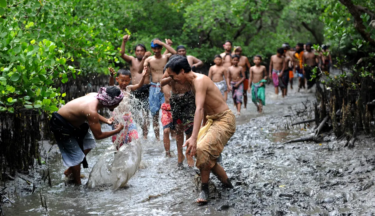 Sejumlah warga terlihat bersemangat saat mengikuti tradisi Mebuug-buugan atau mandi lumpur di desa Kedonganan, Denpasar, Bali (10/3). Mebuug-buugan diadakan sehari usai hari raya Nyepi. (AFP/Sonny Tumbelaka)