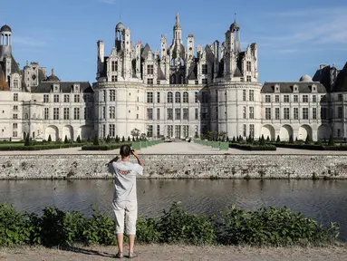 Seorang pengunjung mengambil gambar Kastil Chambord, di Chambord, Prancis pada 22 Juli 2020. Bangunan bersejarah ini merupakan salah satu kastil terbesar di Prancis sekaligus lokasi nyata yang menginspirasi film pertama Beauty and The Beast, 26 tahun lalu. (Photo by Ludovic MARIN / AFP)