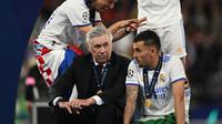 Pelatih Carlo Ancelotti (tengah) berbicara dengan Daniel Cebellos (kanan) saat para pemain Real Madrid merayakan kemenangan final Liga Champions di Stadion Stade de France, Prancis, Minggu (29/5/2022) dini hari WIB. Real Madrid menang 1-0 aas Liverpool di final. (Paul ELLIS / AFP)