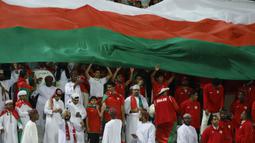 Para pendukung Oman membentangkan bendera raksasa saat Timnas Oman menghadapi Kirgistan pada laga ketiga Grup F Piala Asia 2023 di Abdullah bin Khalifa Stadium, Doha, Qatar, Kamis (25/1/2024). (AFP/Karim Jaafar)