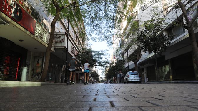 Dua orang berlari melalui jalan raya Hamra yang sepi di pusat Beirut setelah lockdown penuh selama tiga minggu di Lebanon, Minggu (10/1/2021).  Lockdown COVID-19 ini merupakan yang ketiga kalinya di Lebanon sejak pandemi corona tahun 2020. (ANWAR AMRO/AFP)
