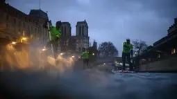 Para peserta Nautic Paddle Race atau lomba dayung sambil berdiri melintas dekat Katedral Notre-Dame di Paris, Minggu (8/12/2019). Sekitar 1000 pesaing ikut serta dalam lomba sejauh 11 kilometer menyeberangi sungai Seine dengan pemandangan kota Paris. (Photo by Olivier MORIN / AFP)