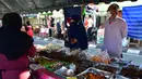 Orang-orang mengenakan masker saat membeli makanan di pasar menjelang berbuka puasa selama bulan suci Ramadan di Provinsi Narathiwat, Thailand, Selasa (5/5/2020). Ramadan kali ini berlangsung di tengah bayang-bayang virus corona COVID-19. (Madaree TOHLALA/AFP)