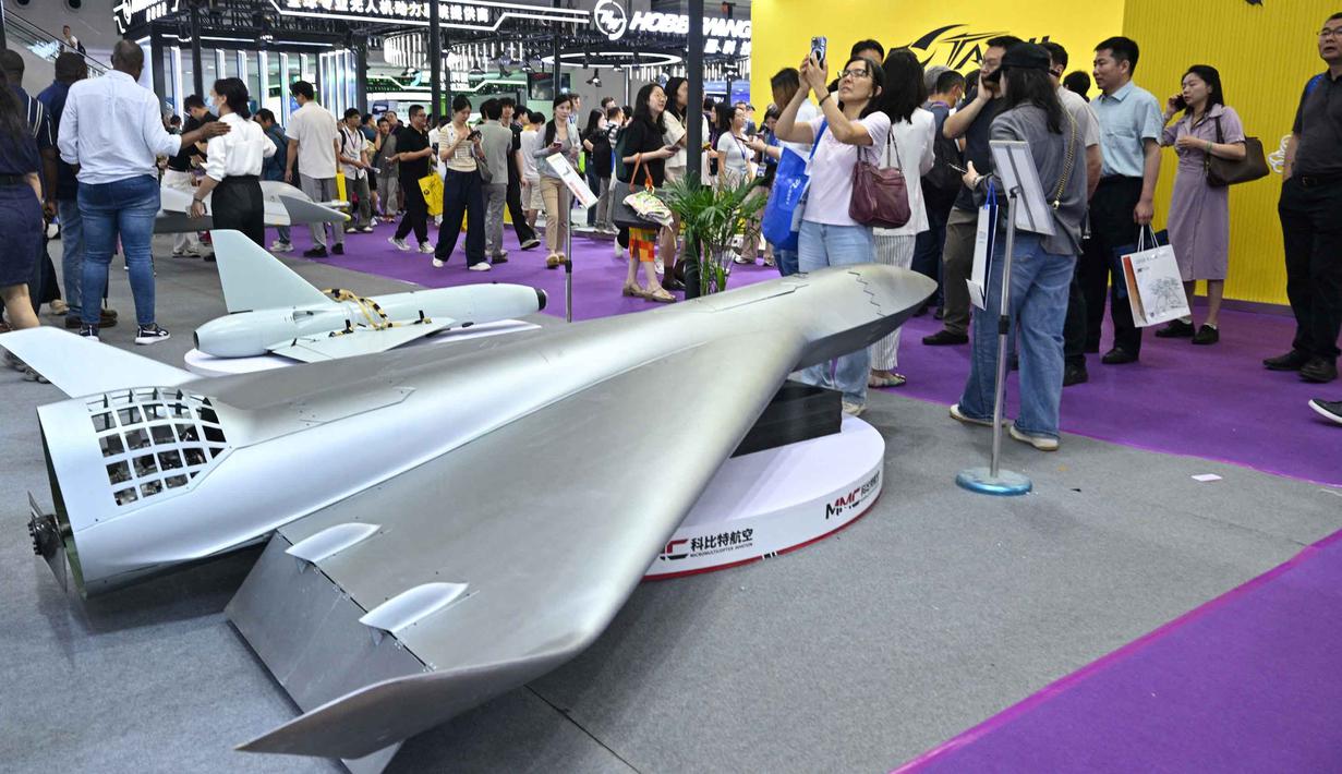 Pengunjung terlihat di samping model drone UAV Flying Eagle H3200 di stan Micro Multi Copter (MMC) selama Drone World Congress (DWC) di Shenzhen pada 21 Mei 2026. (HECTOR RETAMAL/AFP)