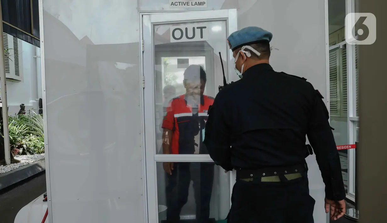 Pengunjung melewati ruang disinfeksi  yang disiapkan di pintu masuk menuju kompleks Istana, Jakarta, Senin (16/3/2020). Pihak Istana Kepresidenan menyediakan ruang disinfeksi berbentuk kubus berwarna putih untuk mendeteksi tamunya yang terjangkit virus corona Covid-19. (Liputan6.com/Faizal Fanani)