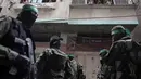 Tentara Hamas mengenakan topeng dan membawa senjata berjaga saat iring-iringan jenazah rekan mereka yang tewas di Deir el-Balah, Jalur Gaza (6/5). Hamas tidak menjelaskan lebih jauh tudingan itu. (AP/Khalil Hamra)