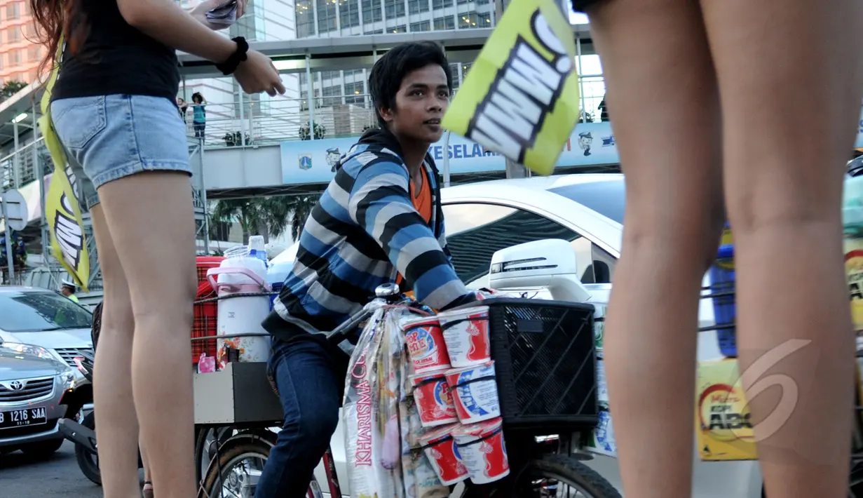 Seorang penjual mie rebus keliling tampak singgah untuk mendapatkan uang dari para wanita cantik di Bundaran HI, Jakarta, Kamis (9/4/2015).  Kegiatan tersebut dalam rangka sosialisasi peluncuran sebuah aplikasi game online (Liputan6.com/Johan Tallo).
