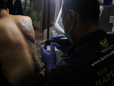Petugas menghapus tato peserta menggunakan sinar laser di Balai Kota DKI Jakarta, Selasa (11/3/2025). (LIputan6.com/Herman Zakharia)