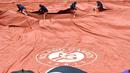Para petugas menutup lapangan Roland Garros saat turun hujan pada turnamen Prancis Terbuka 2016 di Roland Garros, (28/5/2016). (AFP/Miguel Medina)