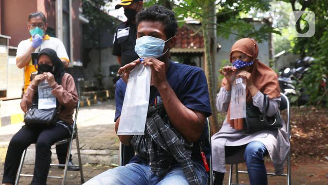 Warga meniupkan kantong saat menjalani tes deteksi COVID-19 dengan metode GeNose C19 usai terjaring razia penggunaan masker di Kelurahan Sudimara Barat, Kota Tangerang, Kamis (27/5/2021). Tes tersebut untuk menekan penyebaran corona di wilayah tersebut. (Liputan6.com/Angga Yuniar)