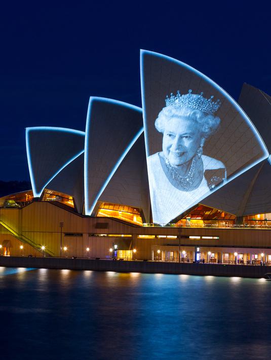 Layar Opera House, landmark ikonik Australia, menyala dengan potret Ratu Elizebeth II di Sydney, Jumat (9/9/2022). Ratu Elizabeth II meninggal dunia pada Kamis 8 September 2022 setelah 70 tahun bertahta. Ia mengembuskan napas terakhirnya di usia 96 tahun. (Photo by Robert WALLACE / AFP)