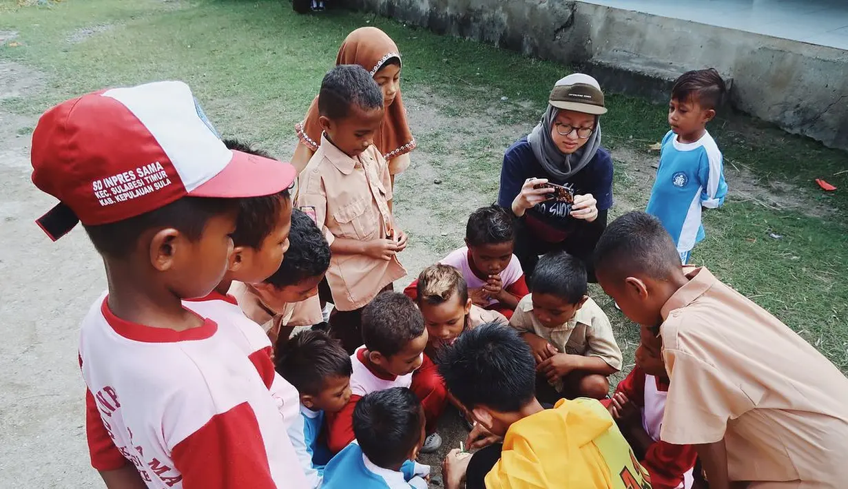 Berbaur dengan masyarakat dan anak-anak di sana, ini adalah potret Gita Savitri saat kunjungi Kepulauan Sula, Maluku Utara. YouTuber sekaligus konten kreator berusia 30 tahun ini ungkap perjalanannya yang penuh tantangan untuk tiba di tempat yang indah ini. Gita menuliskan ia harus naik ferry kurang lebih 14 jam dari Ternate, kemudian harus naik oto kira-kira 3-4 jam buat ke Desa Kabau Darat dan 2 jam ke Desa Sama. (Liputan6.com/IG/@gitasav)