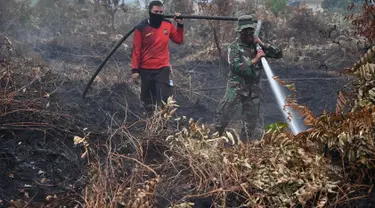 Prajurit TNI dan petugas Badan Penanggulangan Bencana Daerah (BPBD) berusaha memadamkan kebakaran hutan dan lahan di Kabupaten Kampar, Provinsi Riau (12/9/2019). Titik api kebakaran yang terjadi di Indonesia telah melonjak tajam. (AFP Photo/Adek Berry)