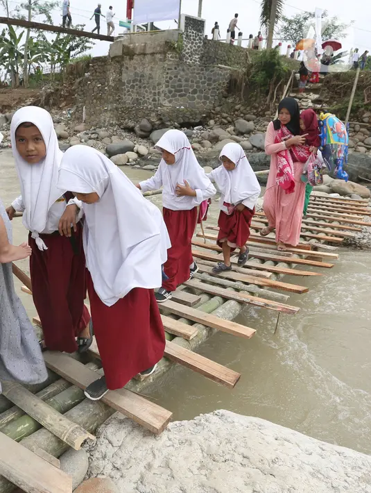 Siswa melintasi jembatan darurat berbahan bambu di Kampung Ciasahan, Desa Sukamaju, Kabupaten Bogor, Kamis (6/2/2020). Pembangunan kembali jembatan Ciasahan yang ambruk akibat banjir bandang pada Rabu (1/1) itu diharapkan mampu memulihkan aktivitas dan perekonomian warga. (merdeka.com/Arie Basuki)
