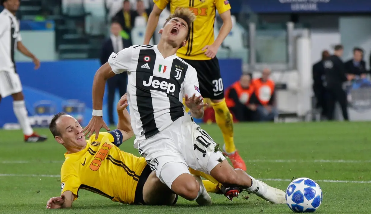 Pemain Young Boys, Steve von Bergen (kiri) menjegal pemain Juventus Paulo Dybala dalam pertandingan Grup H Liga Champions di Stadion Allianz, Turin, Italia, Selasa (2/10). Juventus membungkam Young Boys 3-0 lewat hattrick Dybala. (AP Photo/Luca Bruno)