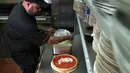 Chief Cook, Fabian Martinez menyelesaikan pembuatan pizza bergambar wajah calon presiden AS dari Partai Republik, Donald Trump dan rivalnya dari Partai Demokrat, Hillary Clinton di Giordano Pizzeria, Chicago, Selasa (27/9). (REUTERS / Jim Young)