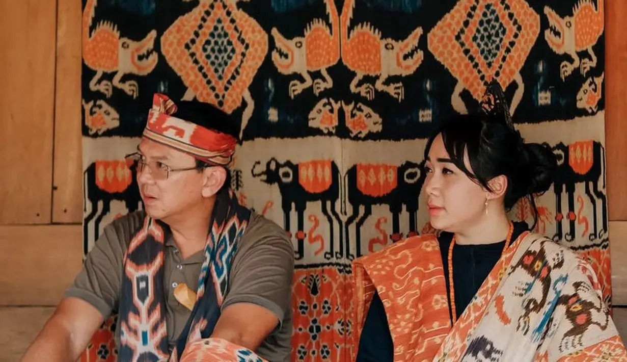 Ahok dan puput mengenakan tenun ikat berwarna oranye dan aksesoris khas Motif Prailiu, Sumba Timur bersama warga setempat.  Lengkap dengan aksesori kalung panjang.  [@pluralljeko]