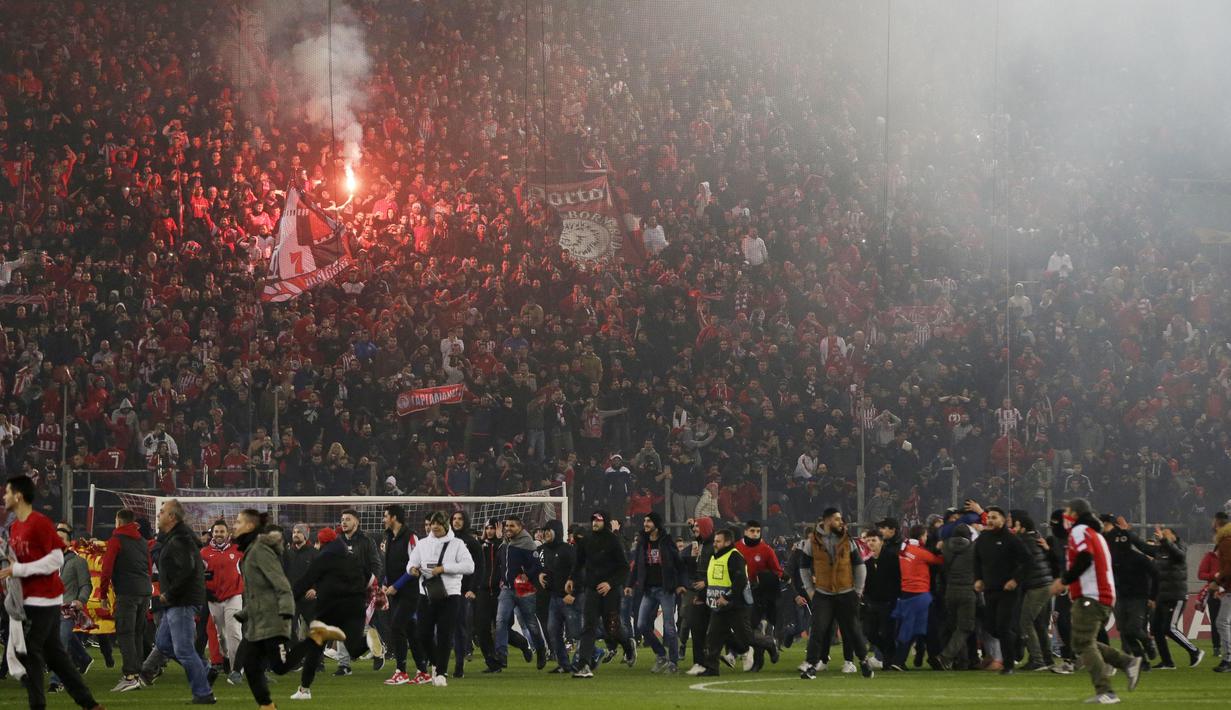 Para suporter Olympiakos turun ke lapangan merayakan kemenangan atas AC Milan pada laga Europa di Stadion Georgios Karaiskakis, Athena, Kamis (13/12). Olympiakos menang 3-1 atas AC Milan. (AP/Thanassis Stavrakis)
