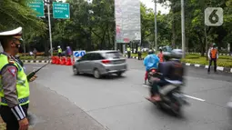 Sejumlah petugas mengatur lalu lintas saat uji coba ganjil-genap di Jalan Margonda Raya, Depok, Jawa Barat, Minggu (5/12/2021). Pelaksanaan uji coba penerapan ganjil genap (gage) di Jalan Margonda Raya pada setiap Sabtu dan Minggu pukul 12.00 hingga 18.00 WIB. (Liputan6.com/Herman Zakharia)