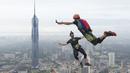 Sepasang pelompat BASE terjun dari Menara Kuala Lumpur selama KL Tower International Jump Malaysia di Kuala Lumpur, Jumat (3/2/2023). Satu persatu peserta pemberani, ada juga yang sekaligus berdua, meloncat sambil membawa parasut masing-masing. (AP Photo/Vincent Thian)