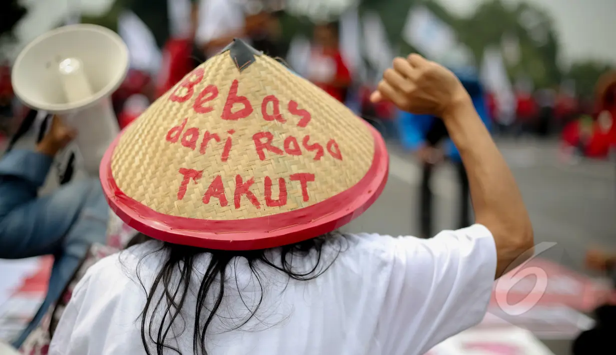 Massa memakai topi caping bertuliskan 'Bebas Rasa Takut' saat aksi tolak hukuman mati yang bersamaan dengan peringatan Hari Buruh (May Day) di depan Istana Merdeka, Jumat (1/5/2015). (Liputan6.com/Faizal Fanani)