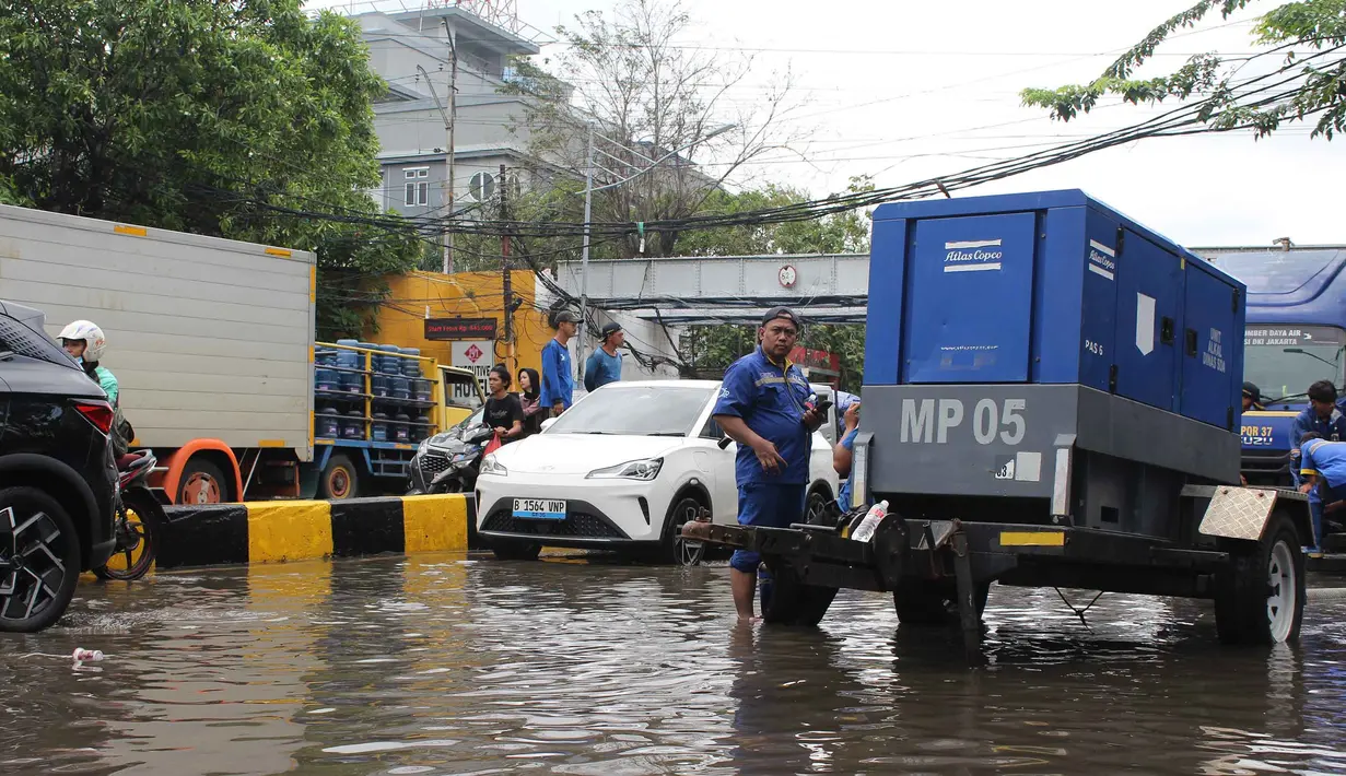 Sejumlah petugas dari Dinas Sumber Daya Air (SDA) DKI Jakarta melakukan upaya pemompaan air untuk mempercepat proses penanggulangan banjir. Tampak dalam foto, petugas Dinas Sumber Daya Air (SDA) DKI Jakarta menyalakan pompa air sebagai upaya penanggulangan genangan banjir yang belum surut di Jalan Gunung Sahari Raya atau tepat di depan Mangga Dua Square, Jakarta, Selasa (13/1/2026). (merdeka.com/magang/Rendi Saputra)