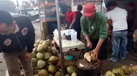 Salah seorang pedagang kelapa muda di bilangan jalan Tarogong Garut, nampak terampil mengupas dan membelah kelapa muda pesanan pembeli menjela buka puasa Ramadan (Liputan6.com/Jayadi Supriadin)