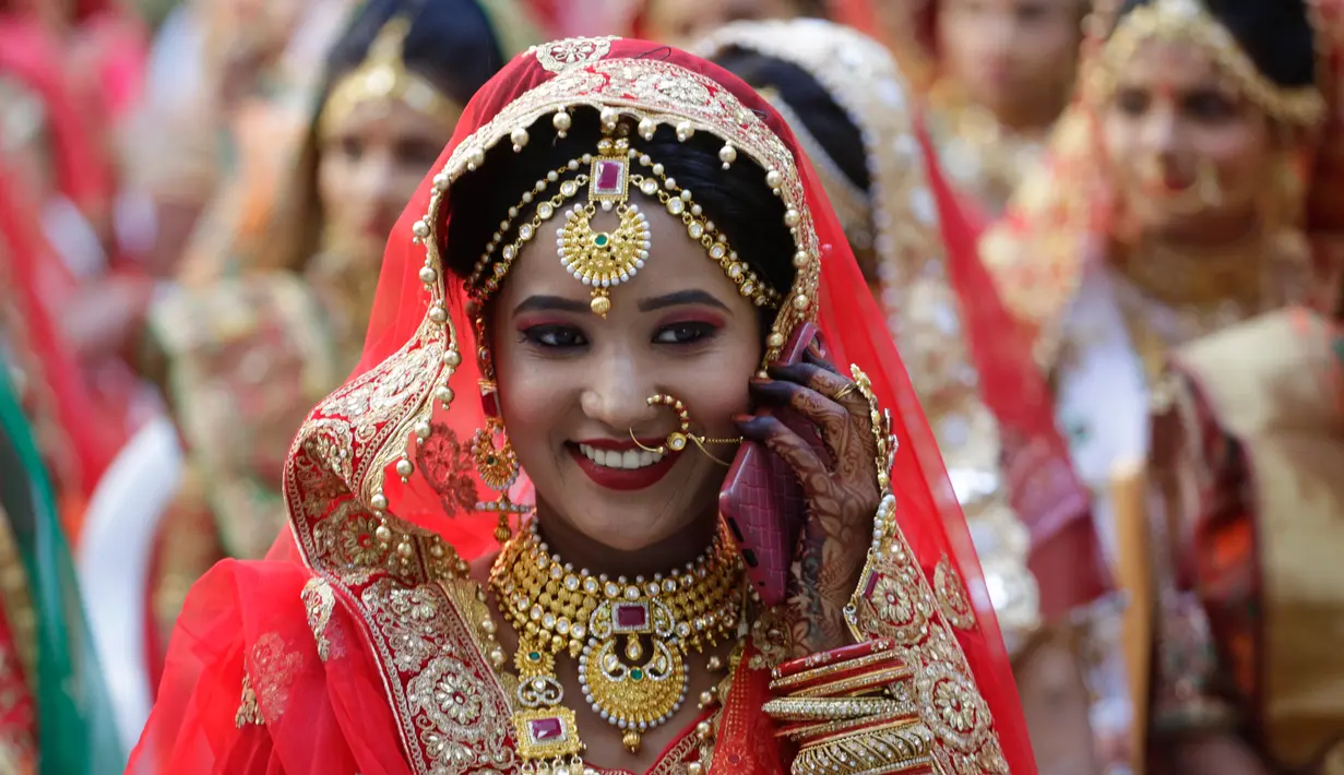 Seorang perempuan tersenyum saat mengikuti nikah massal di Surat, India, Minggu (23/12). Nikah massal ini juga diikuti oleh enam pasangan pengantin Muslim dan tiga pasangan Kristen. (AP/Ajit Solanki)