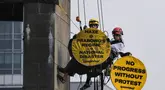 Aktivis Greenpeace Indonesia bergelantungan di Patung Selamat Datang sambil membentangkan poster berisi pesan protes di kawasan Bundaran Hotel Indonesia, Jakarta, Selasa (20/10/2026). Aksi tersebut digelar bertepatan dengan dua tahun pelantikan Presiden Prabowo Subianto. Para aktivis mendesak pemerintah mengambil langkah untuk mengatasi krisis iklim yang kian memburuk dan kenaikan biaya hidup. (BAY ISMOYO/AFP)