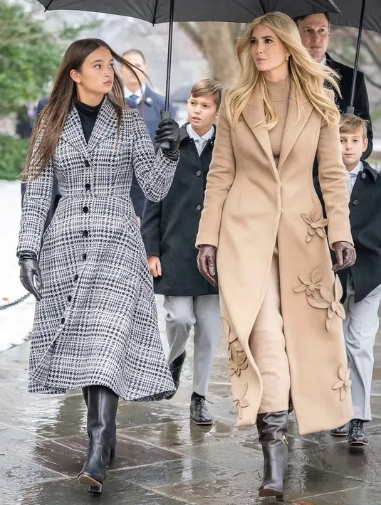 Ia tampil stylish kenakan turtleneck dan celana cokelat berbalut mantel panjang bermotif bunga. Ivanka lengkapi busananya dengan boots dan sarung tangan kulit [@oscardelarenta]