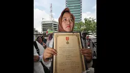 Seorang wanita dari keluarga veteran membawa piagam bintang gerilya saat melakukan unjuk rasa di depan Gedung KPK, Jakarta, Kamis (18/12/2014). (Liputan6.com/Miftahul Hayat)